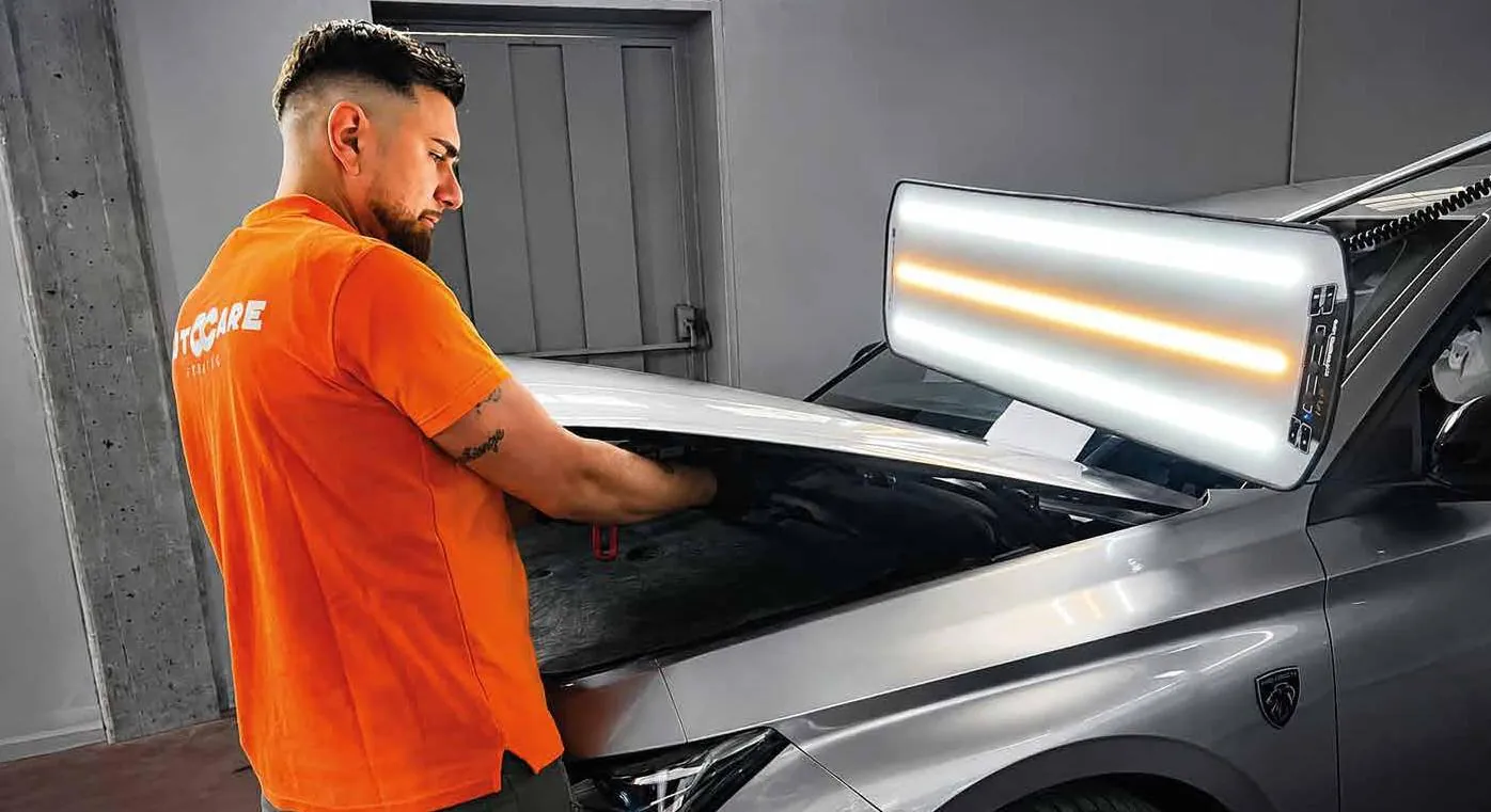 Tecnico al lavoro con la barra luminosa per la riparazione levabolli